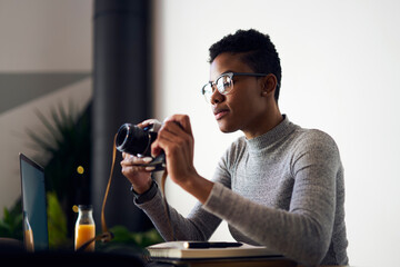 Focused black photographer checking retro photo camera