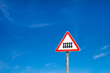 A road sign warning of approaching a railway against a blue sky