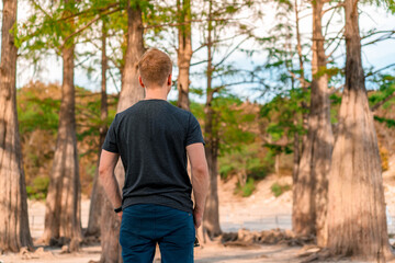 Young male tourist in cypress grove growing in Sukko lake