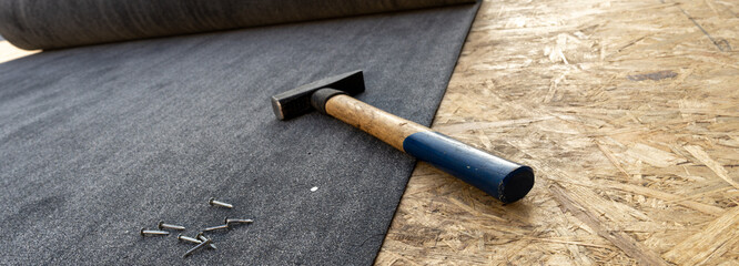 Bituminous waterproofing, hammer, nails, close up. Cut to banner size