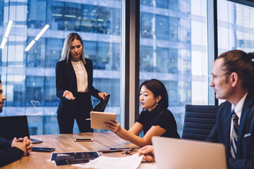 Serious businesswoman discussing project with diverse colleagues