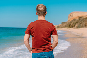 Young blonde man relaxing on a tropical beach, white sand and azure sea