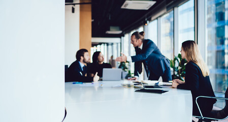 Blurred image of male and female crew of finance experts having meeting table for discussing project planning, professional male executive manager gesture explaining strategy to group employees