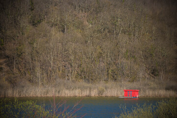 cabane flottante rouge au milieu d'un lac en hiver