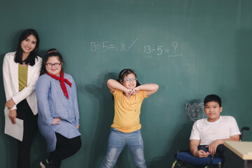 Disabled kids classroom, school boy on wheelchair and down syndrome girls learning and having fun during study at school with teacher, they writing on the blackboard