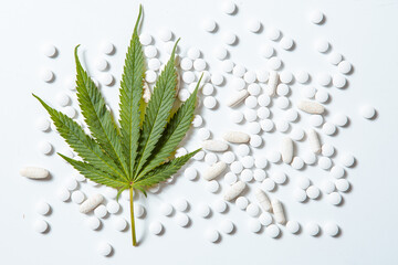 Hemp leaf lying on tablets on white background, top view. Natural dietary supplements