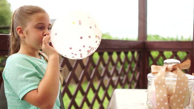 Before the Birthday party. Closeup of a teen girl inflating a white balloon