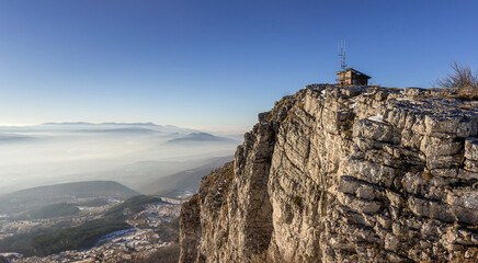 Sunlit rocky summit with ruined building at the top with some remaining snow and golden light of the setting sun
