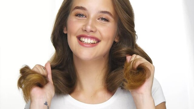 beautiful woman playing with her healthy strong hair and smiling