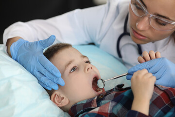 Woman dentist examines child's teeth with metal tools. Dental treatment for children concept.