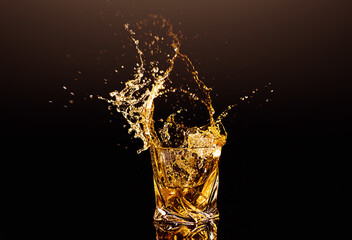 A glass of whiskey with splashes from the ice cube over black background. alcohol splashes. whisky...