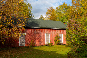 Old storage barn in the country side surrounded by colorful trees during autumn.
