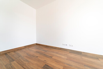 Empty room with dark wooden floating laminate flooring. House interior, wide bedroom or living room space. Newly recently painted new apartment or house. Wood floor. Real state and property management