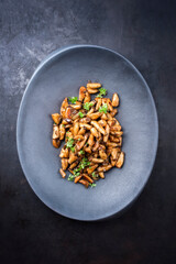 Traditionelle frische gebratene Baby Kräuterseitlinge Pilze mit Kräuter angeboten als Draufsicht auf einem gußeisernen Teller