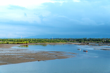 2 fishermen on their respective boats in the tidal sea environment in Lhokseumawe, Aceh, Indonesia.