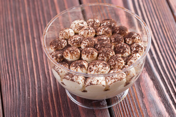 Tiramisu dessert in a glass cup on wooden table