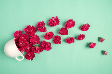 Composition made of beautiful carnations flowers and white cup on a green background. Top view with copy space
