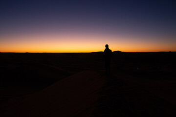 Fototapeta na wymiar A person contemplates during sunset in the desert