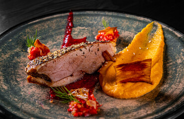 Roasted Duck breast fillets with pumpkin pure in plate on black wooden table background