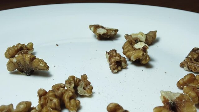 Close up, walnuts faling on the white plate in slow motion. High quality FullHD footage