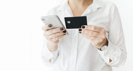 Unrecognizable woman holding black credit card and smartphone, making online payment, online shopping