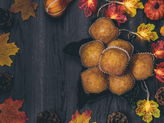 Pumpkin muffins in a platter.
Pumpkin muffins in a dish with autumn leaves, pine cones and a garland around the edges, and in the middle there is a place for text, flat lay close-up.

