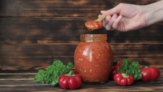 Fresh natural homemade sauce made from peppers, tomatoes and other vegetables on a wooden background.
