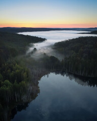 Fototapeta na wymiar Morning fog over a mountainous area from a bird's eye view. Bright colors of dawn and misty river