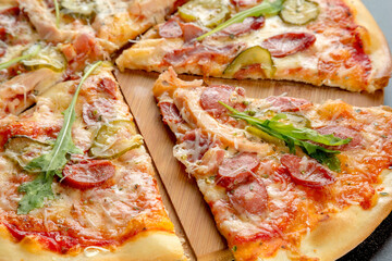 Pizza with ham and mushrooms on a thin crust. Black background.