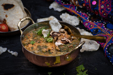 Indian spinach and lentil stew, saag dal, with flat breads on dark table