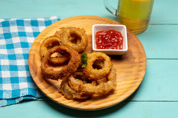 Onion rings with ketchup on turquoise background