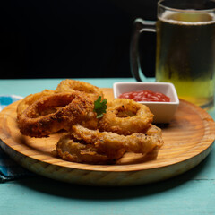 Onion rings with ketchup on turquoise background