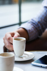 Businessman sitting in cafe, drinking morning coffee and using smartphone