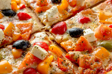 Greek pizza with olives, bell peppers, feta cheese and tomatoes.
