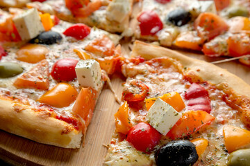 Greek pizza with olives, bell peppers, feta cheese and tomatoes.