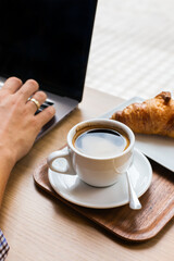 Freelancer sitting in cafe, drinking coffee and using a laptop