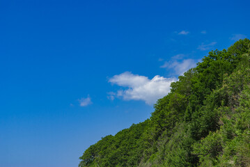 Green mountain against blue sky and white clouds