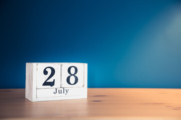 July 28 - white calendar blocks on wooden table against vintage blue background