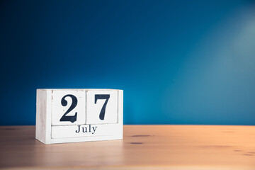 July 27 - white calendar blocks on wooden table against vintage blue background