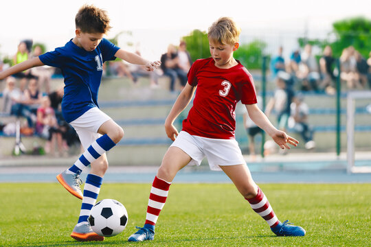 Happy kids compete in football game. Running soccer players. Competition between players running and kicking football ball. Football school. Young boys playing soccer game. Kids having fun in sport.
