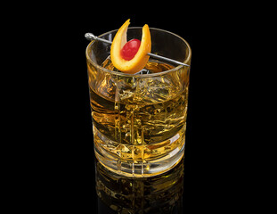 Whiskey glass with ice and drink skewer with orange slice and cherry. Black background.
