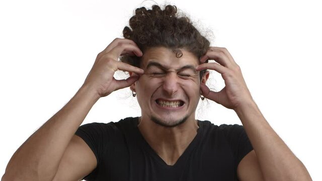 Close-up of tensed young caucasian man with curly hair and beard, standing in black t-shirt, shaking from anger, grimacing bothered, head exploding from annoyance