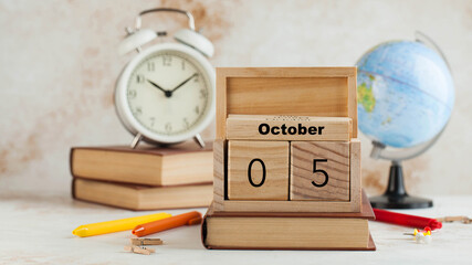 Wooden calendar October 5 on a stack of books, globe. World teacher's day
