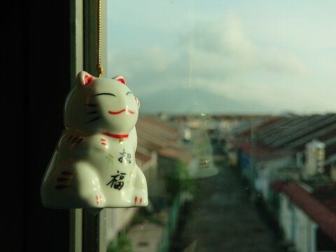A fortune cat hanging by the window of a house bedroom