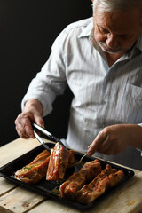Selective focus. The chef puts the marinated pork ribs on a baking sheet. Barbecuing ribs.