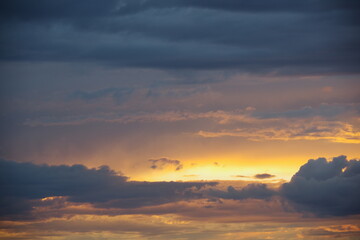 Dark storm clouds with colorful reflections of the setting sun.  Scenic storm clouds lit by the last rays of the sunset.