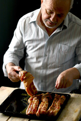 Selective focus. The chef puts the marinated pork ribs on a baking sheet. Barbecuing ribs.