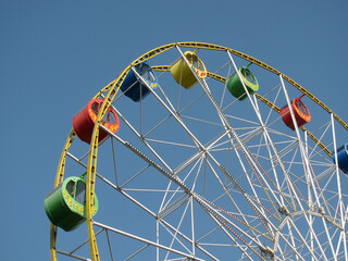 Ferris wheel with colorful booths against the blue sky on a clear day.