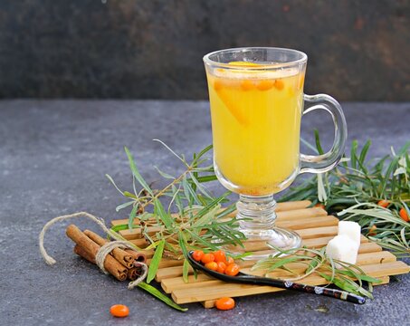Brewed tea from sea buckthorn and orange slices in a glass mug on a black concrete background. Sea buckthorn recipes. B