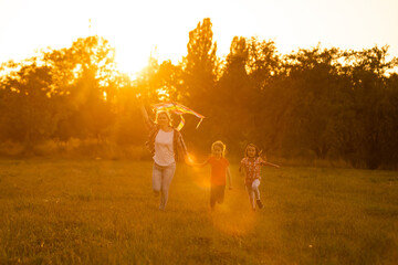 Obraz na płótnie Canvas mothers and daughters in a field at sunset with an kite